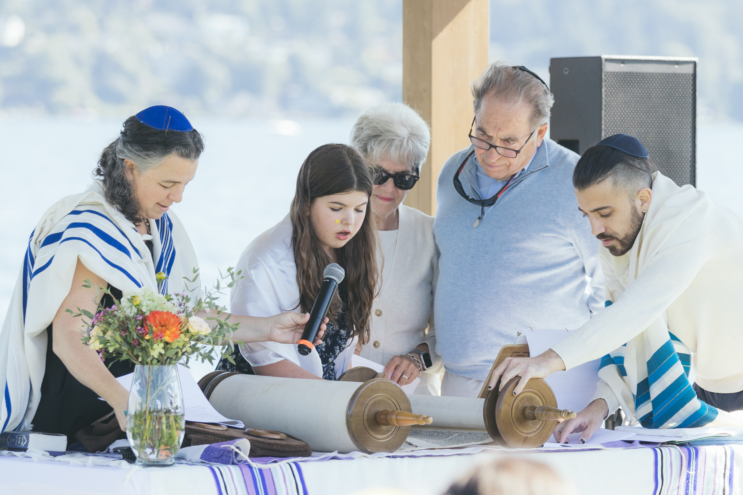 A girl celebrating her Seattle bat mitzvah on a summer day by Lake Washington. The ceremony captures her joy, surrounded by family and friends.